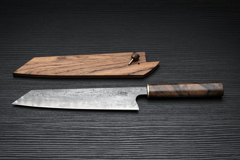 A handmade kitchen knife with a wooden handle, beside its wooden sheath